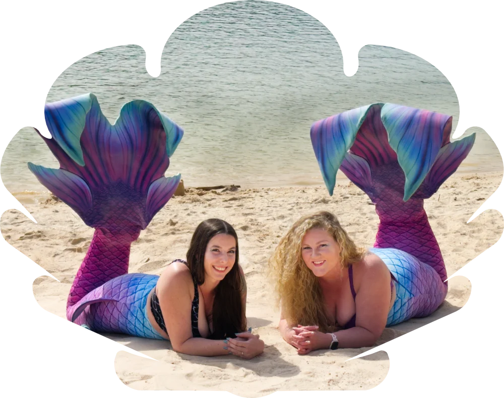 The Bopsie Mermaids laying on a beach with their tails up